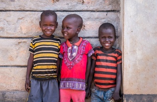 3 children smiling standing in front of a wall