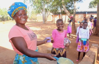 Volunteer in Malawi serving food to children