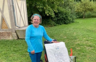 Woman in blue t-shirt standing in campsite with trailer and sign