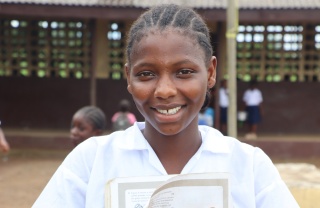 Isatu, a girl from Liberia, smiling outside her school