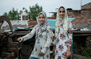 Two young sisters, Fatima and Soni, stand outside in India