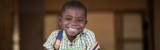 Smiling child holding mug of Mary's Meals porridge