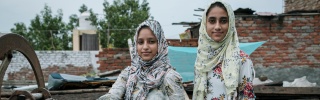 Two young sisters, Fatima and Soni, stand outside in India