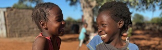 Happy children in Mozambique outside eating Mary's Meals