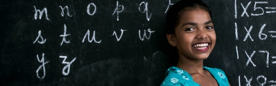 Image of a girl in India standing in front of a chalkboard