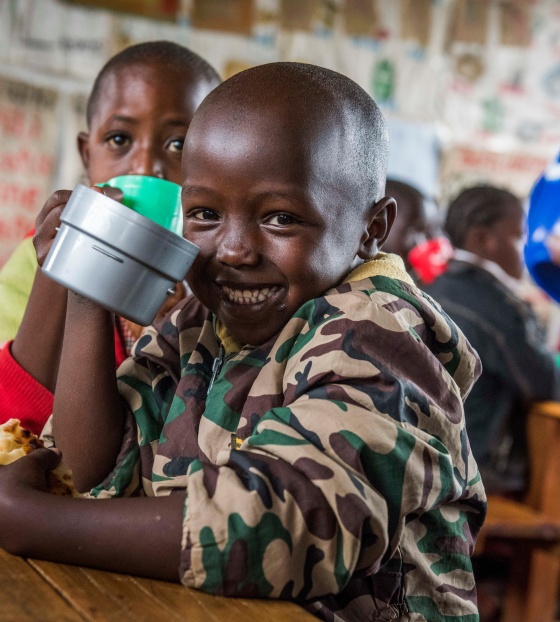 A smiling child poses with a mug in a classroom in Kenya