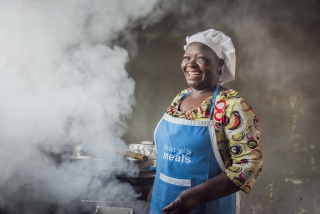 A smiling volunteer prepares food