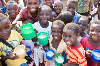 Smiling group of children with mugs of porridge