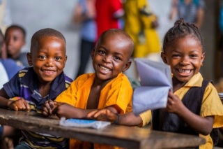 Three smiling children in a classroom in Liberia