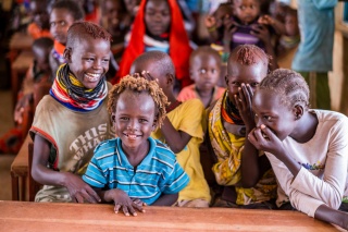 Children in a classroom sitting a table and laughing with each other