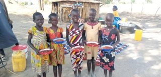 Smiling school children holding plates of maize and beans