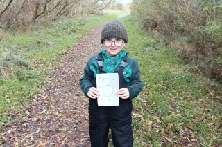 Mikey, a young Mary's Meals supporter, shows off a sign signalling that he has walked 3k out of 10k on a fundraising walk for Mary's Meals