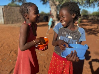 Happy children in Mozambique outside eating Mary's Meals