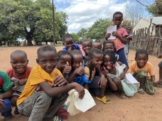 A group of happy children siting outside in Mozambique