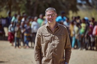 Magnus-MacFarlane Barrow standing in front of a group of children in Ethiopia