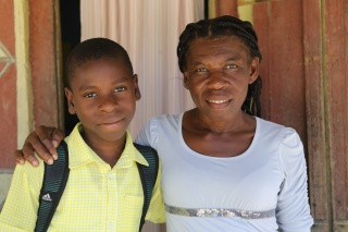 Billy, a boy who receives Mary's Meals in Haiti, stands with his mother, Diulene